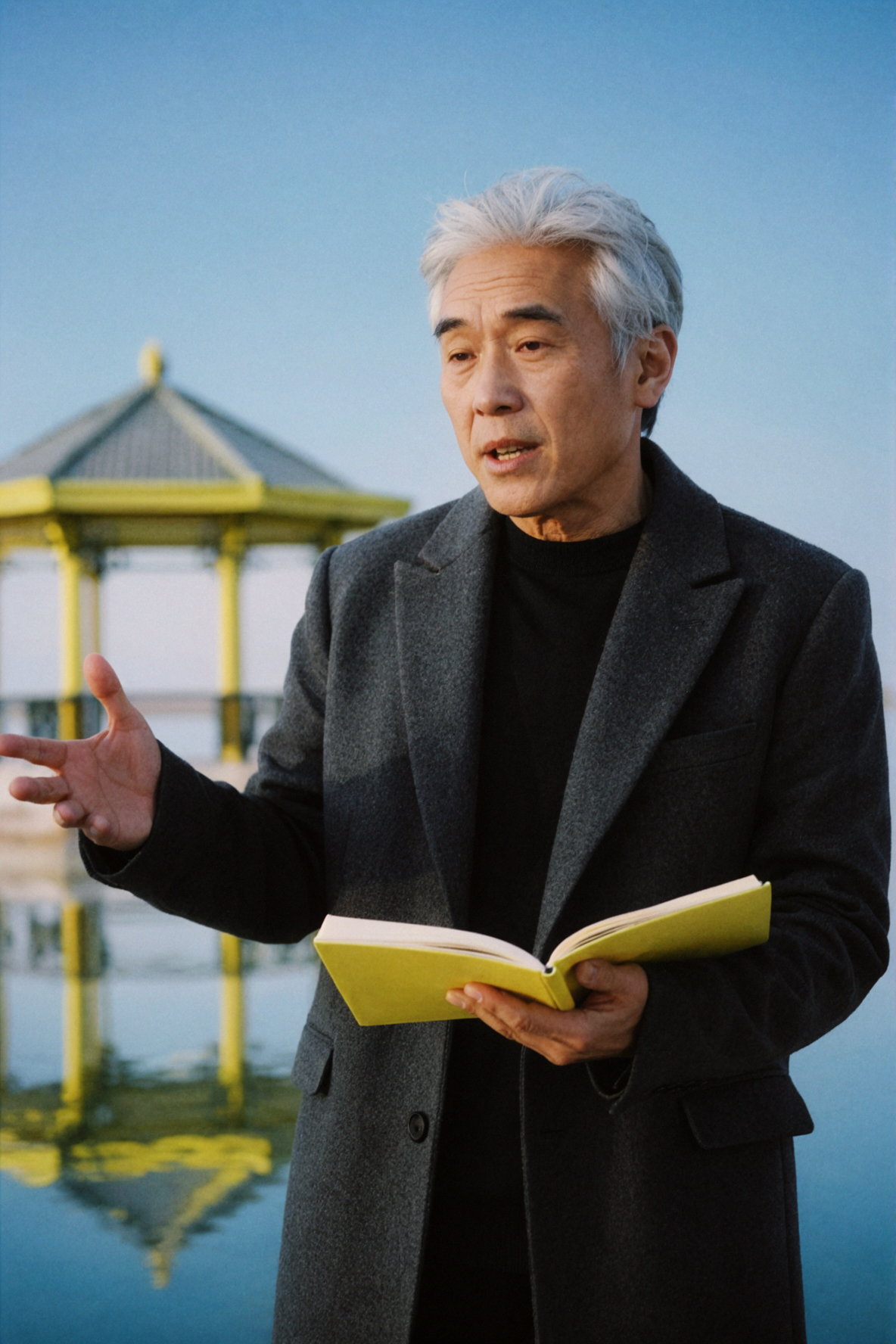 Poète adulte est-asiatique aux cheveux argentés récitant sur un pont · film négatif couleur — AI image creation